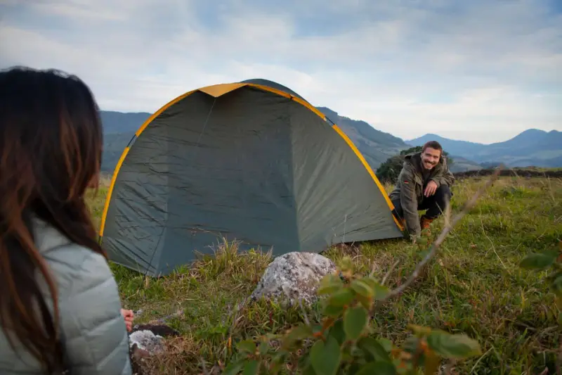 Mann und Frau biwakieren in Deutschland. Sie bauen ein Zelt in den Bergen auf, die Landschaft ist wunderschön.