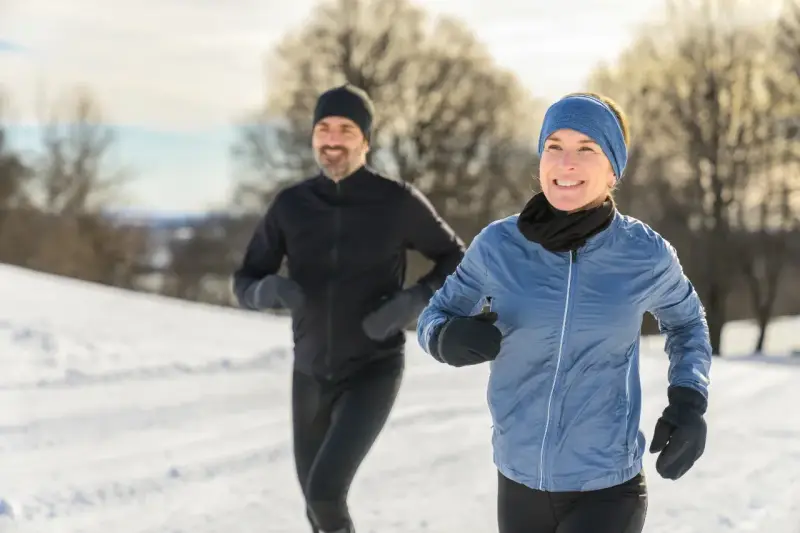 Ein Paar genießt das Laufen im Winter. Sie tragen passende Winterkleidung, um sich warm zu halten.