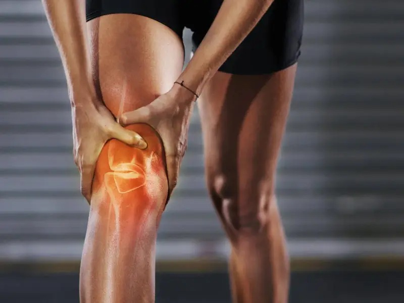 Person hält schmerzendes, dickes Knie. Was tun bei Knieproblemen? Rote Hitze zeigt Entzündung.