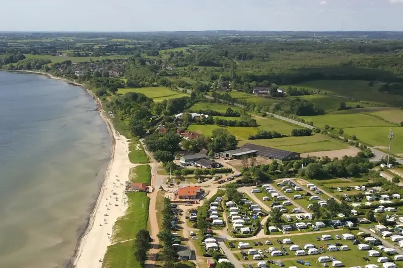 Luftaufnahme eines Campingplatzes in Schleswig-Holstein mit Wohnmobilen und Zelten, direkt am sandigen Strand und dem Meer gelegen.